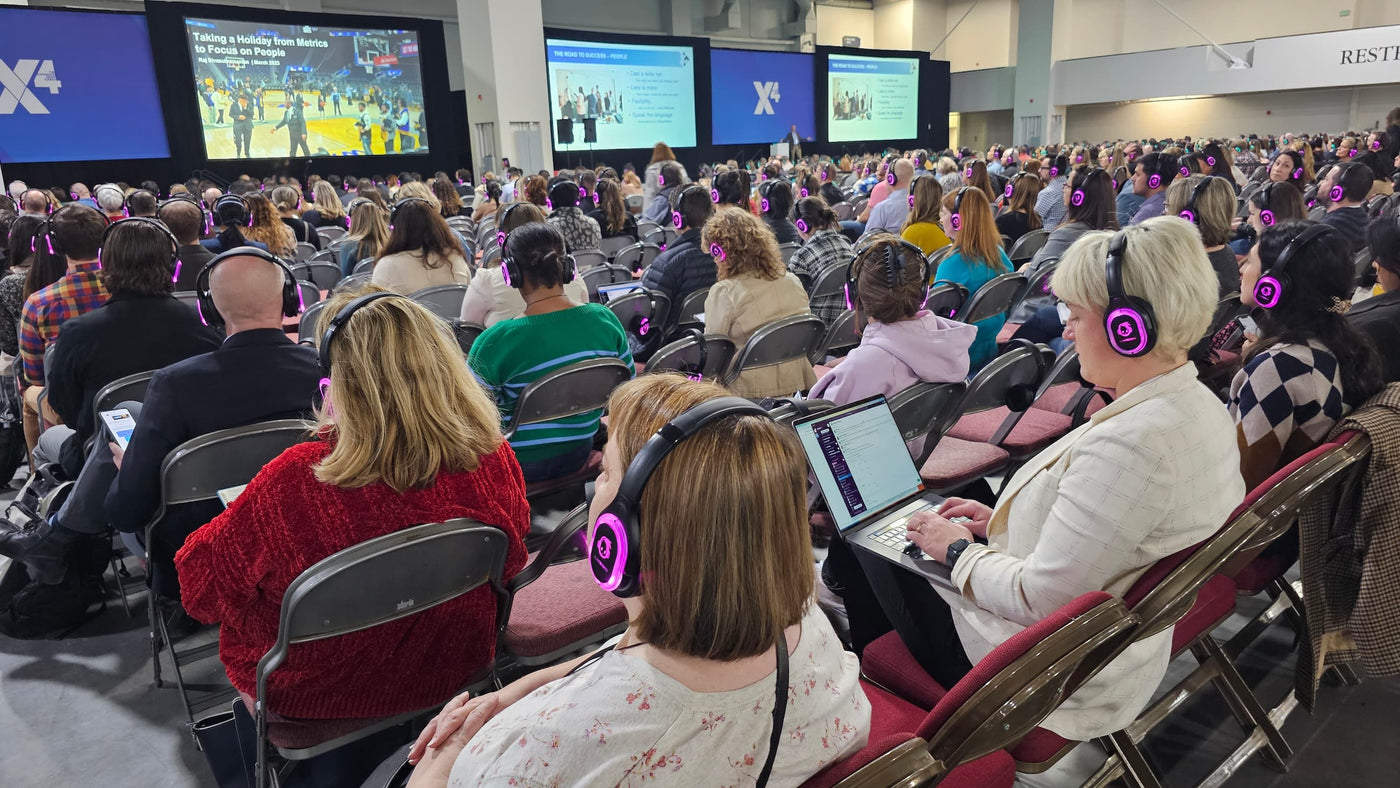 Quiet Events Silent Disco headphones for Conferences with a group of people looking at a screen with headphones on.