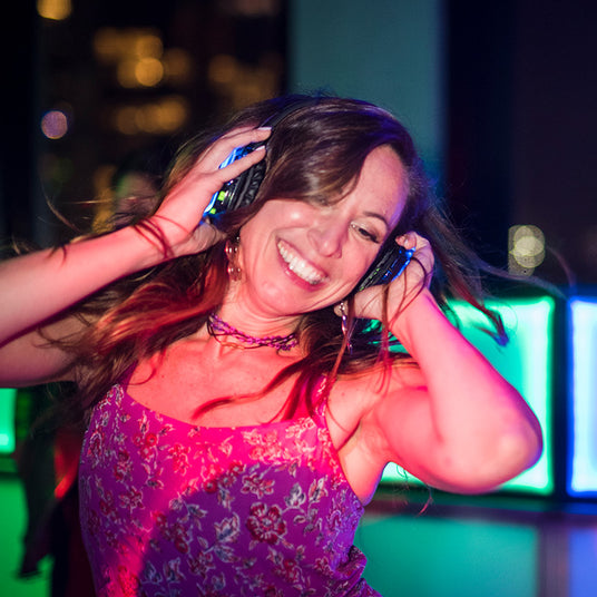 Quiet Events Silent Disco headphones for bachelorette. A happy girl dancing and enjoying her time wearing headphones.