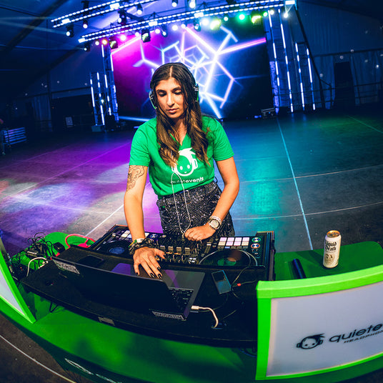 Quiet Events Silent Disco headphones for bachelorette. A female DJ mixing on a stage wearing wearing headphones.