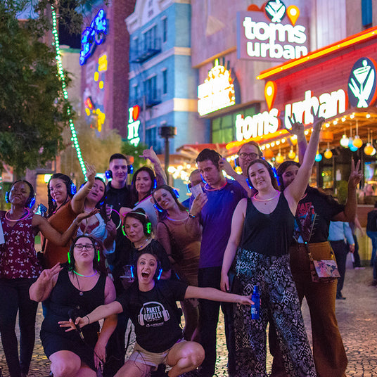 Quiet Events Silent Disco headphones for bar crawls. A group of people gather together outdoors with headphones having fun.