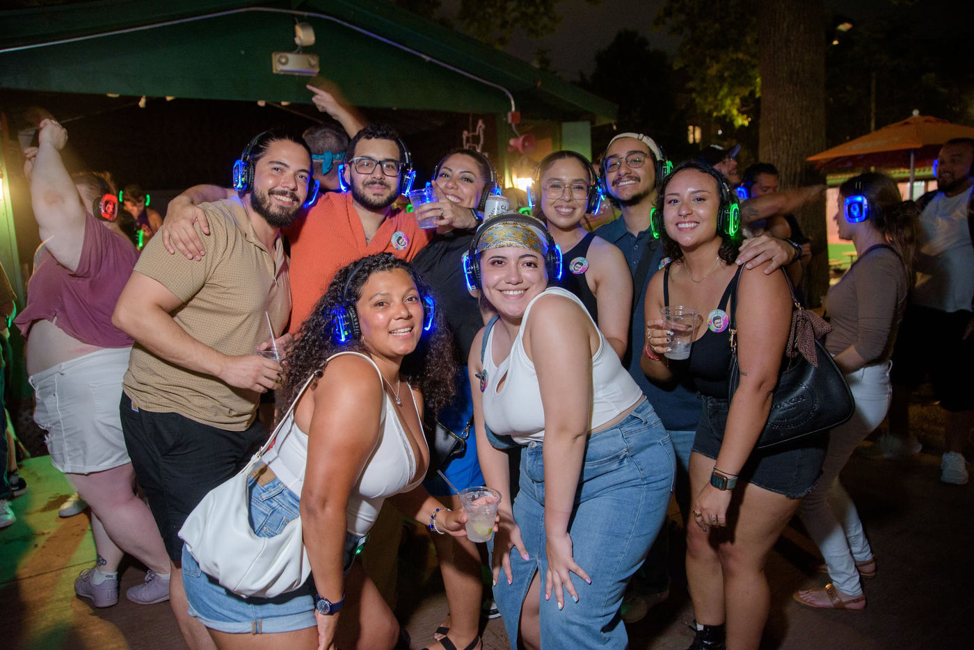 Quiet Events Silent Disco headphones for camps. A group of people together having fun posing for a picture with headphones.
