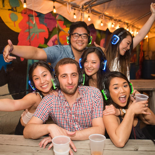 Quiet Events Silent Disco headphones for camps. A group of young adults together having fun and wearing headphones.