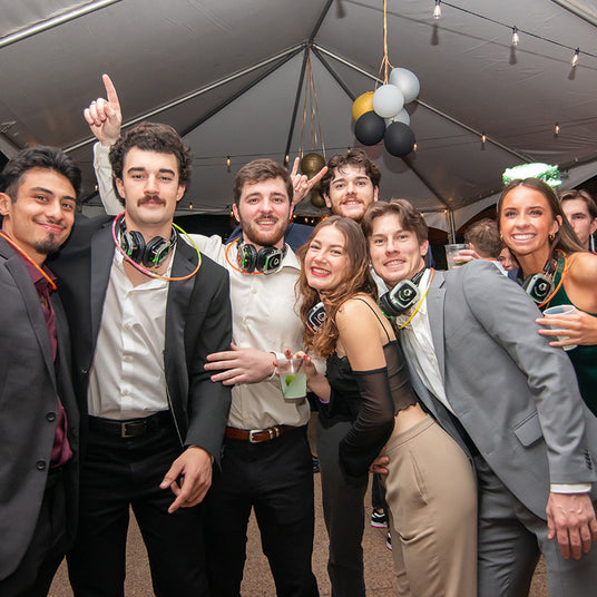 Quiet Events Silent Disco headphones for corporate. A group of professionals together posing for a picture at a party with headphones.