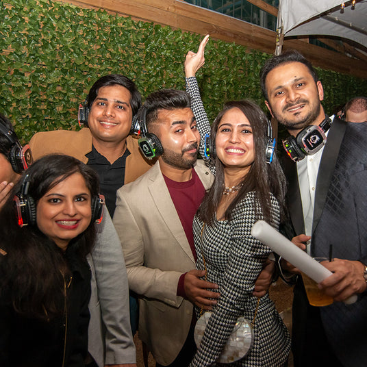 Quiet Events Silent Disco headphones for corporate party. A group of professionals gather together at a party with headphones.