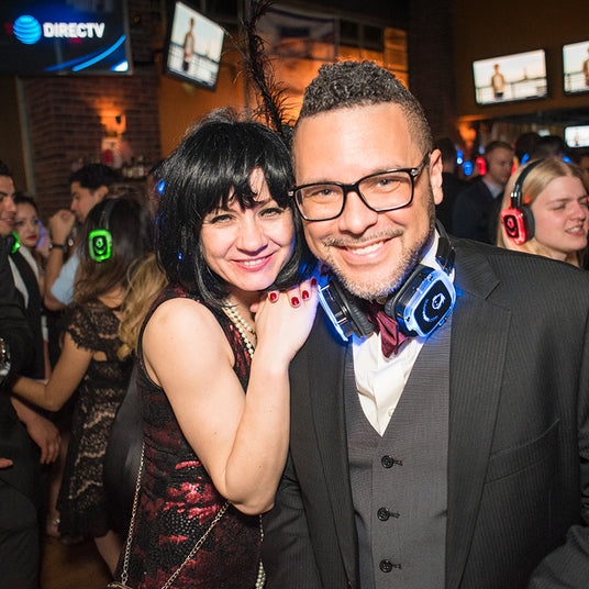 Quiet Events Silent Disco headphones for corporate party. A professional couple posing in the middle of the floor with headphones.