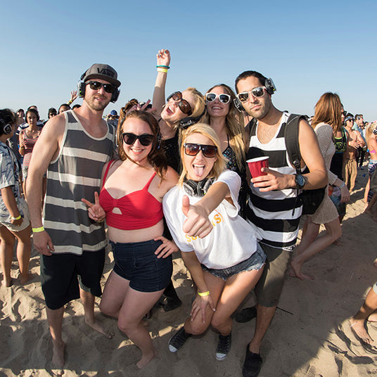 Quiet Events Silent Disco headphones for dance parties a group of people at the beach having fun and posing.