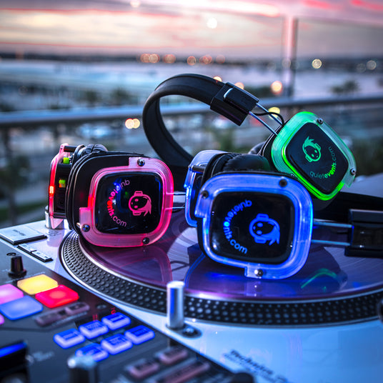 Quiet Events Silent Disco headphones for dance parties in a group laying on DJ mixer with various colors.