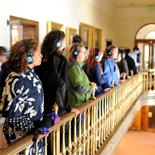 Quiet Events Silent Disco headphones for dance parties a group of people over looking a balcony wearing headphones.