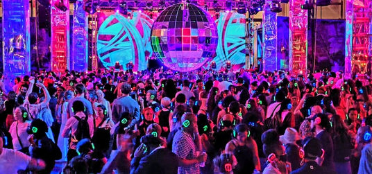 Quiet Events Silent Disco headphones for fairs a group of people dancing in an open space with a large disco ball