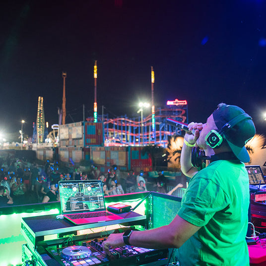 Quiet Events Silent Disco headphones for festivals a DJ holding a mic on stage at an amusement park
