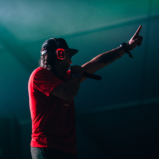 Quiet Events Silent Disco headphones for festival a Red DJ pointing to the crowd and speaking on a Microphone