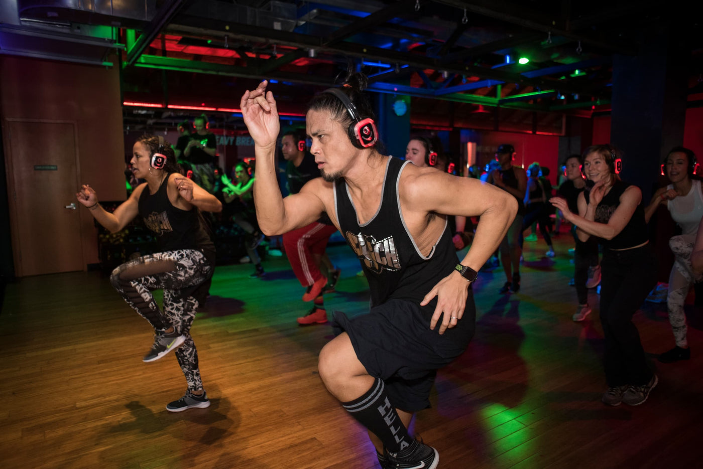 Quiet Events Silent Disco headphones for fitness. An Instructor and his students working out on a floor gym wearing headphones.