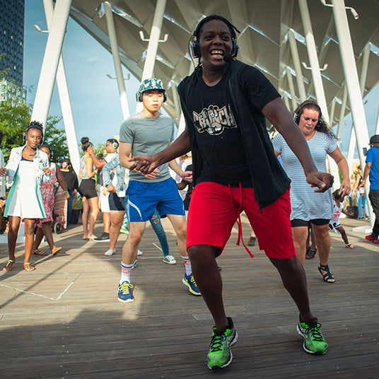 Quiet Events Silent Disco headphones for health and wellness. An instructor having fun teaching a class outdoors and everyone wearing headphones.