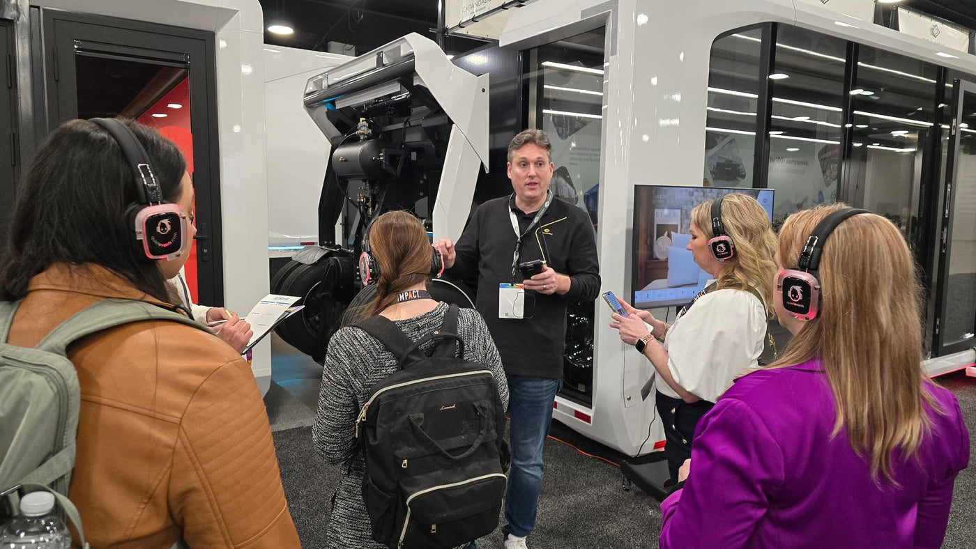 Quiet Events Silent Disco headphones for convention a group of people standing with headphones listening to a speaker next to equipment.