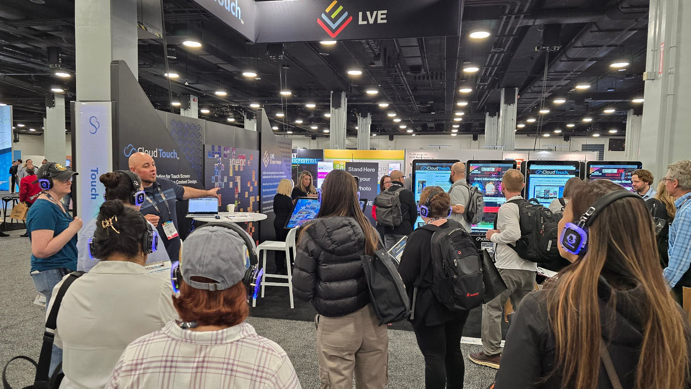 Quiet Events Silent Disco headphones for expo a group of people wearing headphones listening to speaker at a booth