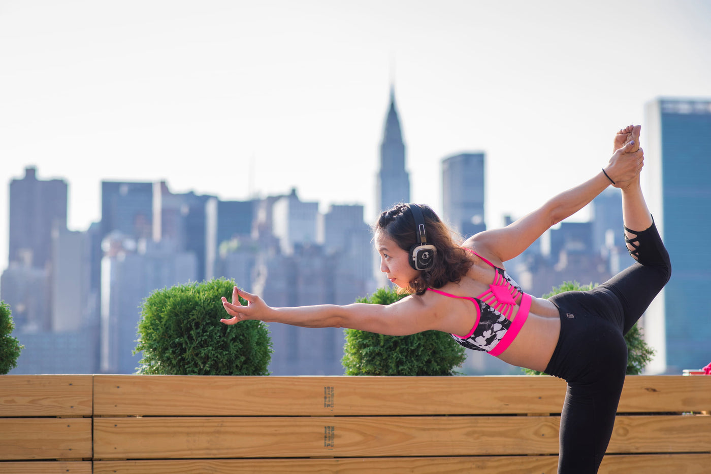 Quiet Events Silent Disco headphones for fitness and wellness. A yoga student posing in a position outdoors wearing headphones.