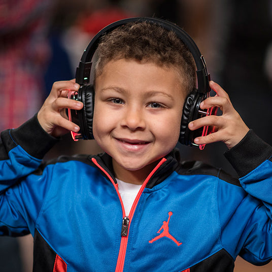 Quiet Events Silent Disco headphones for home and young male child wearing headphones holding each side with his hands