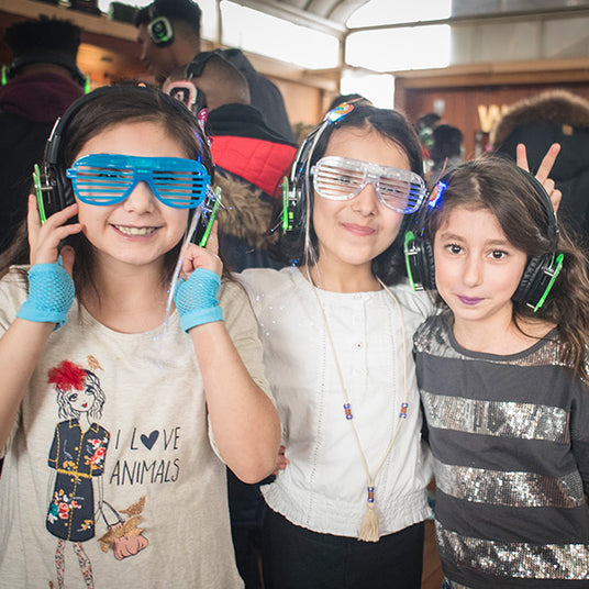 Quiet Events Silent Disco headphones for home and group of three female children at a party together wearing headphones and party gear.