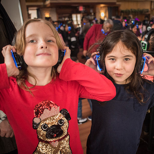 Quiet Events Silent Disco headphones for home and two children having fun and holding their headphones over their ears