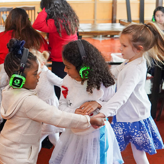 Quiet Events Silent Disco headphones for home and a group of three female children holding hands and playing together with headphones