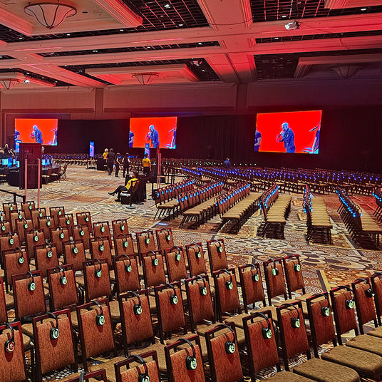 Quiet Events Silent Disco headphones for meetings a convention room filled with chairs and headphones and screens.