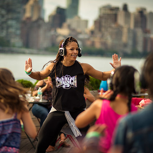 Quiet Events Silent Disco headphones for schools and universities. An aerobic instructor with headphones given a class to her students.