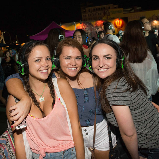 Quiet Events Silent Disco headphones for schools. A group of young girls having fun in an outdoor setting wearing headphones.