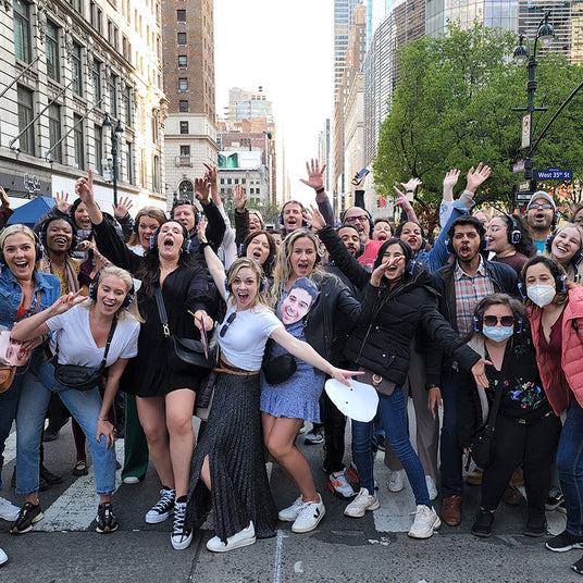 Quiet Events Silent Disco headphones for schools and universities. A group of people gather together cheering with their hands up having fun and headphones.