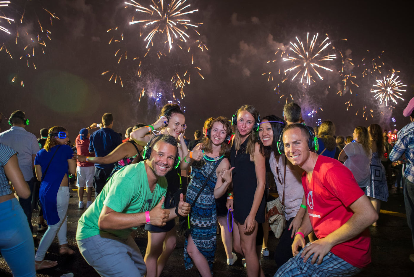 Quiet Events Silent Disco headphones for traveling. A group of people having fun at a fireworks display wearing headphones.