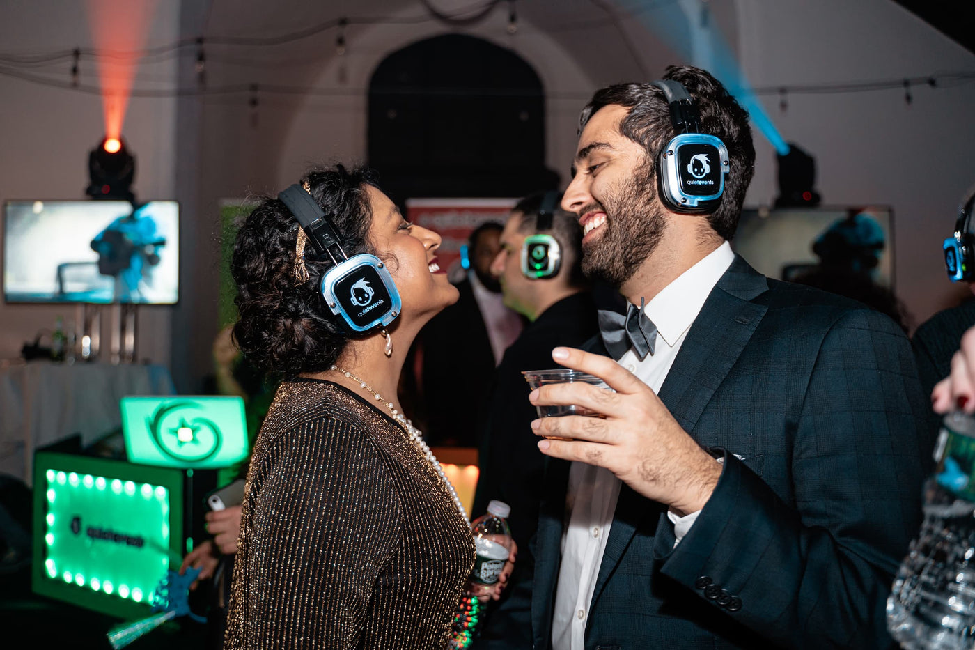 Quiet Events Silent Disco headphones for hotels. A couple well dress happy and having fun with headphones.