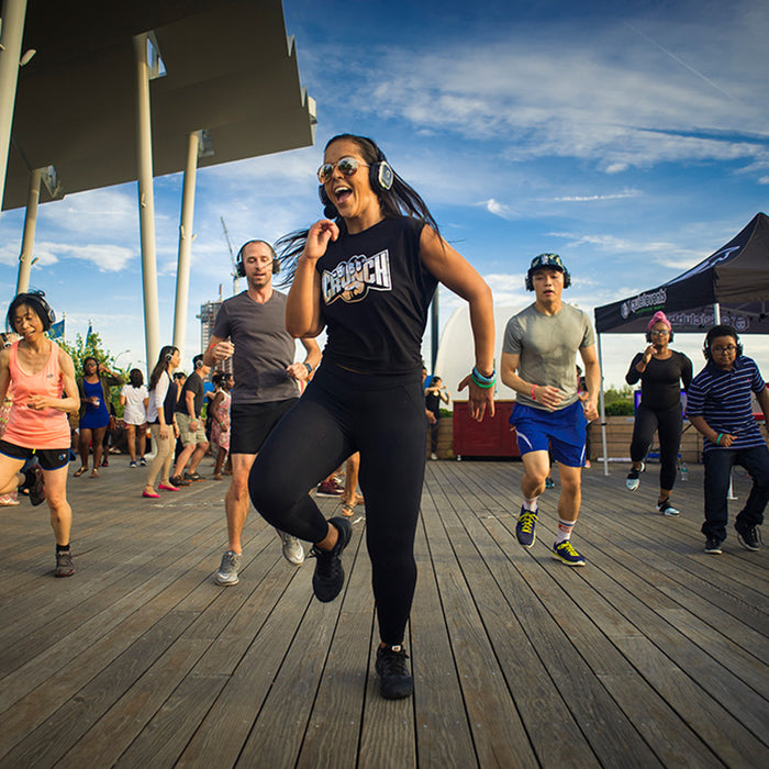 Quiet Events Silent Disco headphones for fitness instructor dancing with a group people outdoors with headphones.