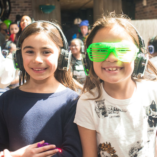 Quiet Events Silent Disco headphones for bar mitzvah.  Two young little girls having fun and smiling wearing headphones.