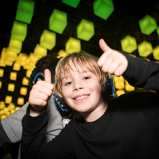 Quiet Events Silent Disco headphones for bar mitzvah.  A young boy posing for a picture with two thumbs up and wearing headphones.