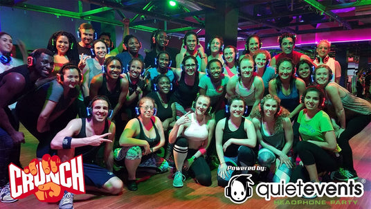 Quiet Events Silent Disco headphones for fitness.  A group of people posing after an aerobics class wearing headphones.