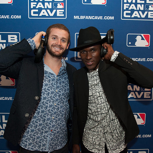 Quiet Events Silent Disco headphones for sporting events.  two gentleman posing for a picture with headphones with a MLB background.