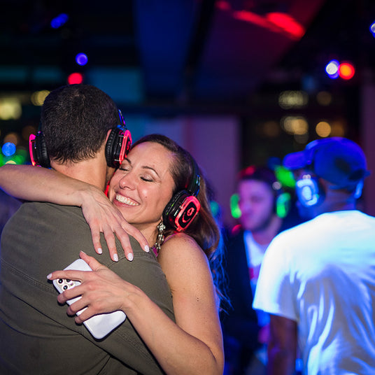 Quiet Events Silent Disco headphones for a wedding.  A couple dancing, hugging and happy together wearing headphones.