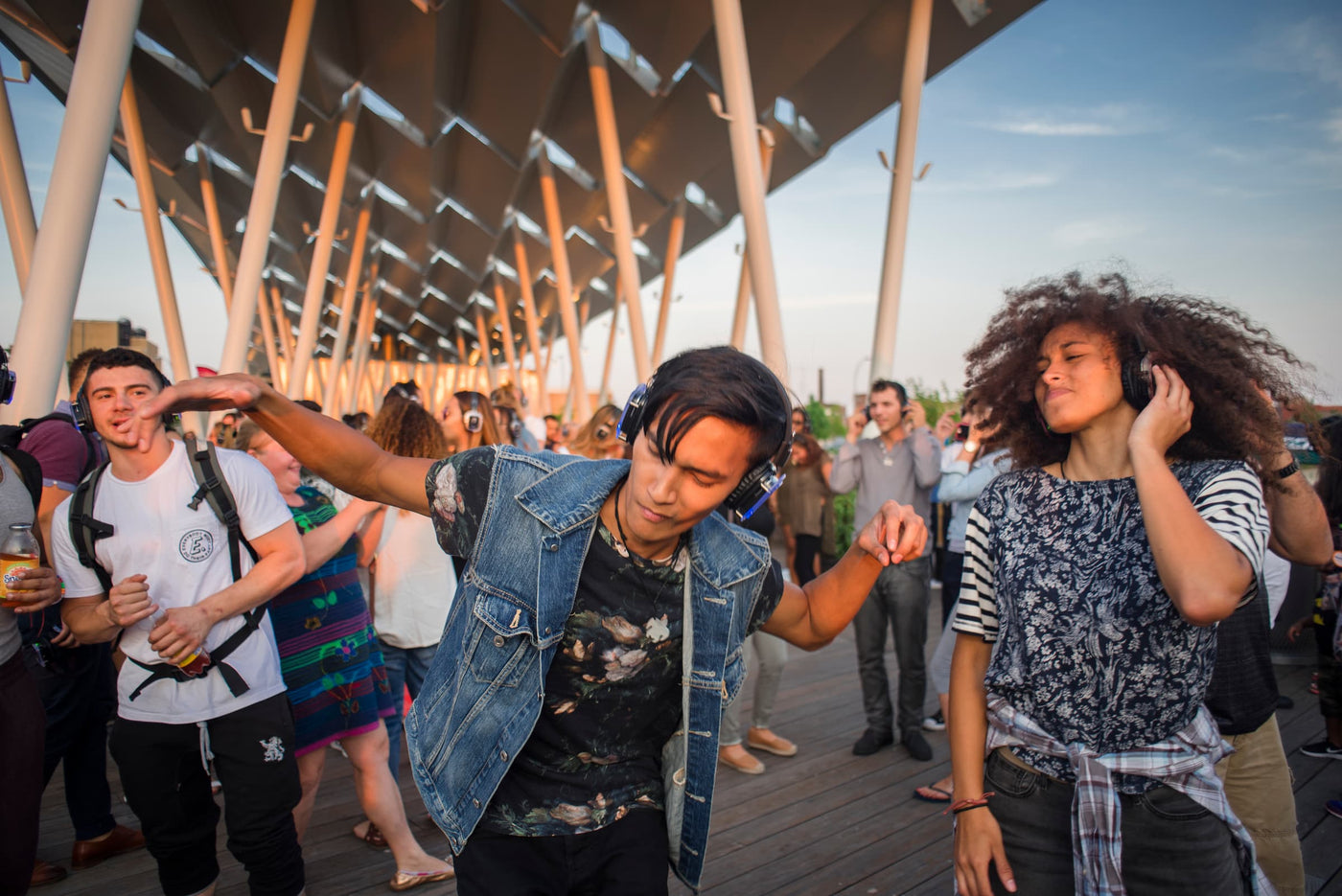 Quiet Events Silent Disco headphones for Property Management.  A group of young adults dancing and having fun outdoors with headphones.